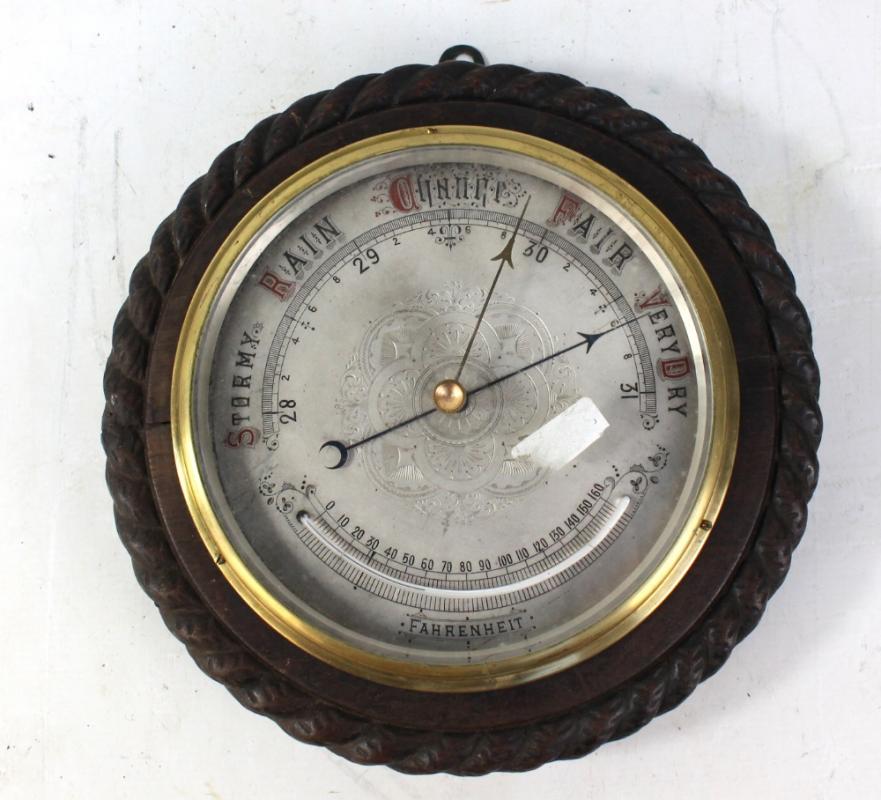 An early 20th century oak circular barometer with silvered dial and ...